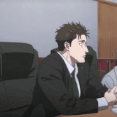 a man in a suit and tie is sitting at a table with his hands folded