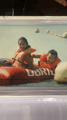 a man and a woman are in a red raft that says ubri on it