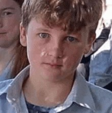 a young boy in a blue shirt is looking at the camera while sitting next to a girl .