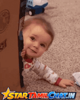 a baby peeking out of a cardboard box with a star tamilchat.in logo in the corner
