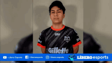 a young man wearing a gillette shirt stands in front of a libero esports banner