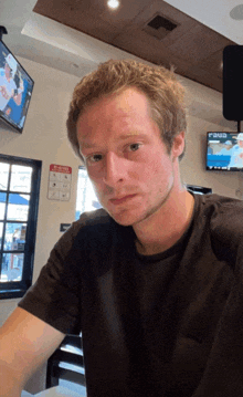 a man in a black shirt is sitting in front of a tv that says pause