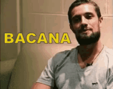 a man with a beard is sitting in front of a wall with the word bacana written on it