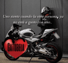 a man leaning against a wall next to a motorcycle with a heart that says catubela