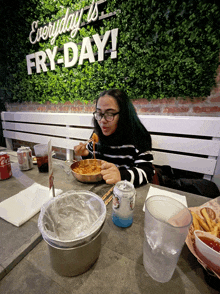 a woman sits at a table eating a meal in front of a sign that says fry-day