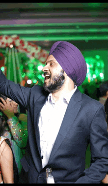 a man wearing a purple turban and a blue suit