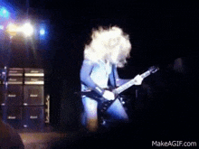 a man is playing a guitar on a stage in front of a stack of amps .