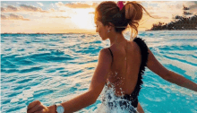 a woman in a black swimsuit is splashing in the water