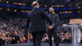 a man in a suit shakes hands with another man in front of a crowd at a hall of fame