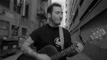 a man playing a guitar in a black and white photo with a sticker on his shirt that says ' california ' on it