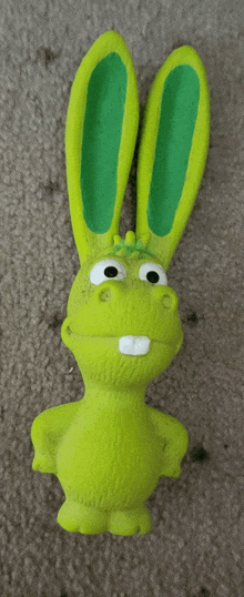 a green bunny toy with green ears is laying on the floor