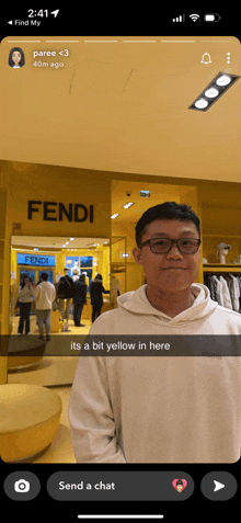 a man in a white hoodie stands in front of a fendi store