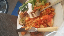 a plate of rice and vegetables with a fork and knife on it