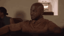 a bald man is sitting on a couch in a living room with a woman .