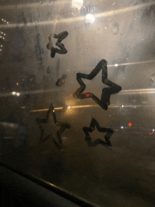 a few stars are drawn on a window with water drops