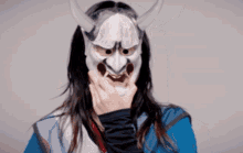 a woman wearing a white mask with horns on her face