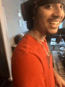 a man wearing a red shirt and a black hat smiles for the camera