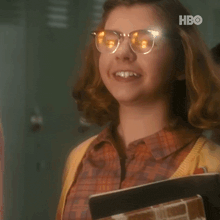 a young girl wearing glasses and a yellow sweater is smiling .