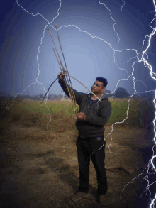 a man in a green sweatshirt is standing in a field with lightning strikes behind him