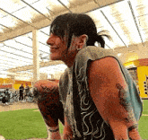 a woman with tattoos on her arms is sitting on the grass in a gym .