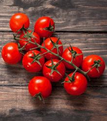 a bunch of cherry tomatoes on a vine on a wooden table