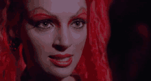 a close up of a woman 's face with red hair and red makeup