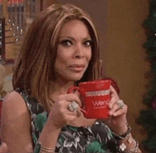a woman is holding a red coffee mug that says ' wendy ' on it .