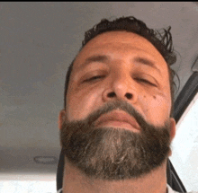 a man with a beard is sitting in the car with his eyes closed