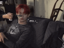two boys are sitting on a couch and one of them has red hair