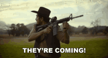 a man in a cowboy hat holding a gun with the words they 're coming behind him