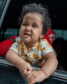 a baby making a funny face while looking out the window