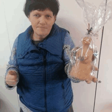 a woman in a blue vest is holding a doll in a plastic bag .