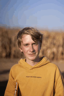 a young man wears a yellow hoodie that says positive and happy on the front