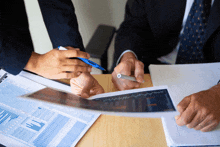 a man is holding a pen while looking at a piece of paper