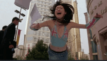 a woman with her arms outstretched is wearing a blue top with the union jack on it