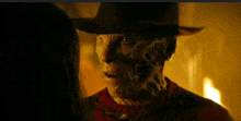 a man in a cowboy hat is talking to a woman in a dark room