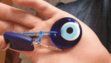 a person is holding a keychain with a blue evil eye