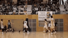 a basketball game is being played on a court with a sign that says aoyama gakuin university basket ball team