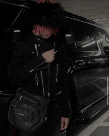 a man with red hair is standing in front of a car