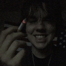 a young man is smoking a cigarette and smiling in the dark .