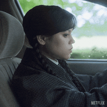 a woman is sitting in the back seat of a car with a netflix logo on the side