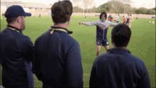 a group of men are standing on a soccer field and one of them is wearing a jacket with the letter s on it