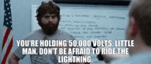 a man with a beard is holding 50,000 volts , little man .