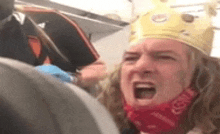 a man wearing a crown and a bandana is yelling at another man on a plane .