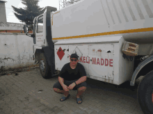 a man is squatting in front of a truck that says keli-madde