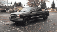 a black pickup truck is parked in a parking lot with leaves on the ground and a street sign that says n. johnson