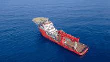 a large red ship in the ocean with a helipad on top of it