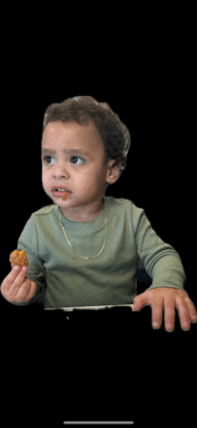 a baby is holding a piece of food in his hand and looking at the camera