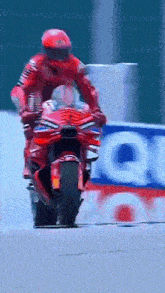a man is riding a red motorcycle in front of a sign that says lubricants