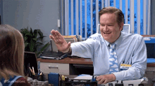 a man in a blue shirt and tie is giving a high five to a woman in an office .